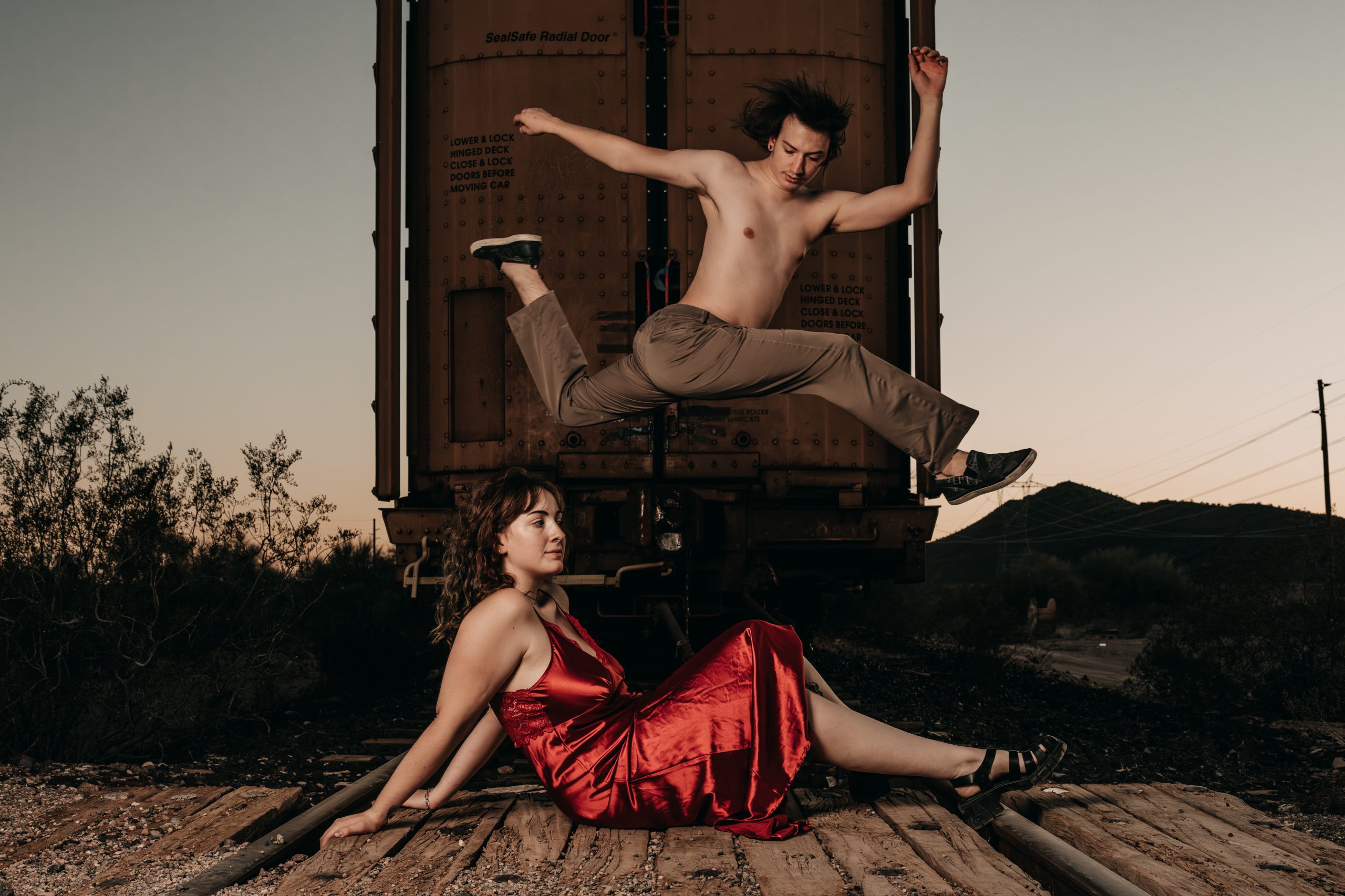 Couples boudoir photo of CJ and Arrie embracing beside a wooden fence on a ranch near Buckeye Arizona